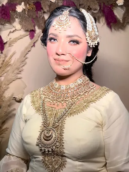A full view of a stunning Muslim bridal look. The intricate outfit and jewelry are complemented by flawless, elegant makeup.