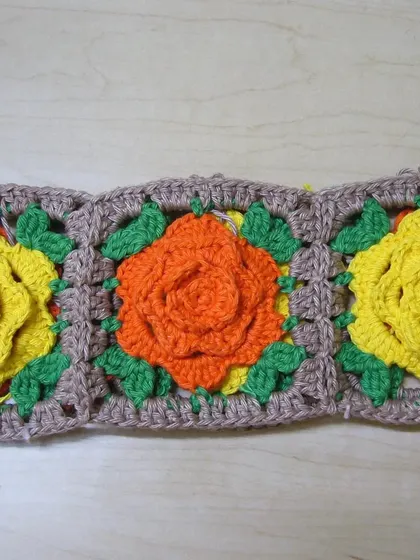 Here are three rose granny squares joined together in a row, forming the side panel of the basket. I alternated between yellow and orange roses.