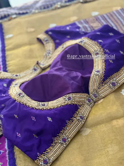 A purple blouse with a simple embroidered neckline.