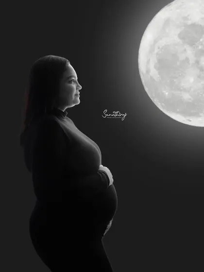 A contemplative solo silhouette of a mother-to-be looking towards the moon. This black and white shot is filled with a sense of wonder and anticipation.