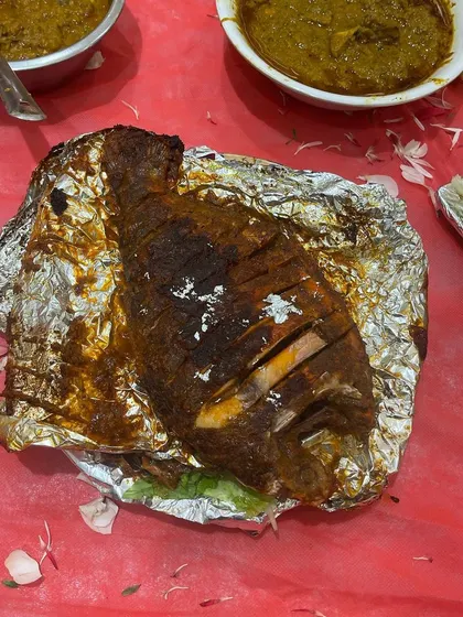 A whole grilled fish, wrapped in foil to keep it moist and flavorful. This is a fantastic centerpiece dish for any seafood lover's table.