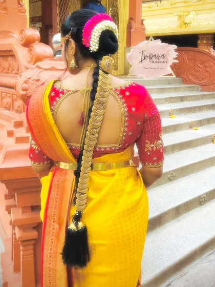 A classic South Indian bridal hairdo featuring a long, thick braid accessory known as 'jade'. This is a quintessential look for a traditional wedding ceremony.