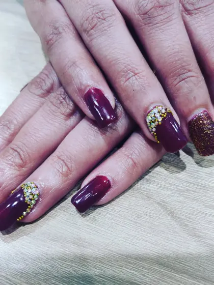 A deep wine-colored nail set with glitter and stone accents. This is a rich and glamorous option for a winter wedding or a cocktail party.