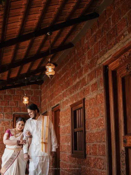 The couple walks arm-in-arm along a rustic brick corridor, a candid moment from their special day.