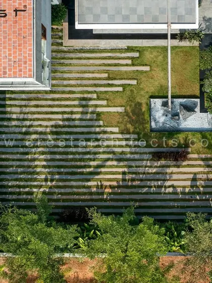 An aerial "top-down" photograph of the landscape design. The geometric lines of the stone pathways contrast with the organic forms of the lawn and water feature, creating a perfectly planned and visually striking composition.