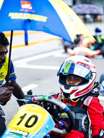 A mechanic holds an umbrella for a young driver on the grid, showing our attention to every detail.