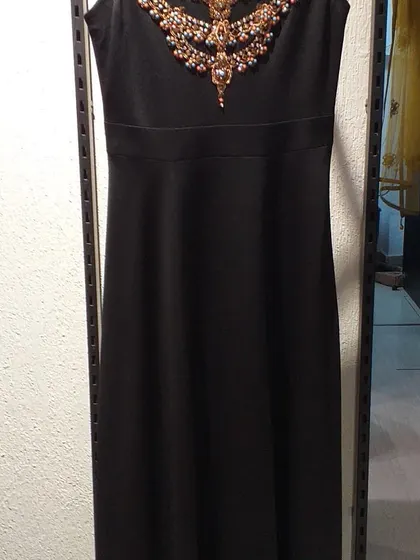 A classic black sheath dress elevated by an ornate, jewel-encrusted neckline. This is a perfect cocktail dress that combines simplicity with a touch of opulence.