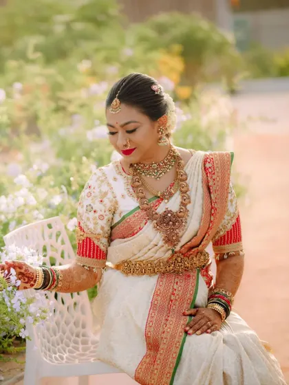 A close-up of Deekshitha's bridal look. The intricate embroidery on her puff-sleeve blouse is visible, along with her beautiful temple jewelry.