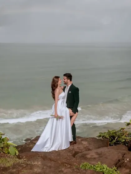 A wide shot of the couple on a cliff, with the dramatic Goan coastline stretching out behind them.