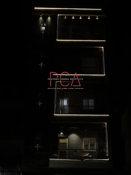 A minimalist night view of The Cursive Abode, where the darkness conceals the building mass and only the illuminated outlines of the balconies are visible.