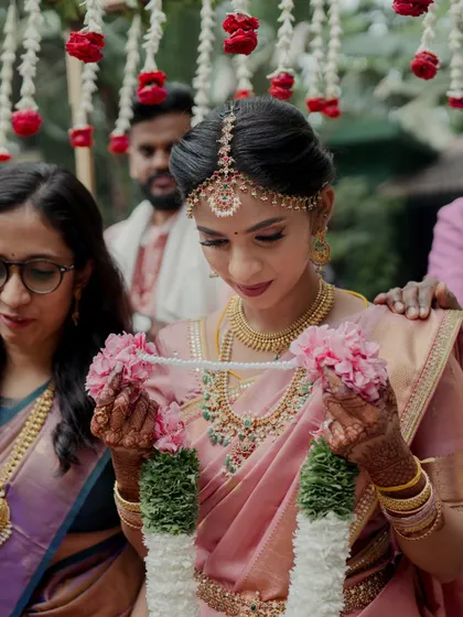 The bride holding a floral garland during a wedding ritual.