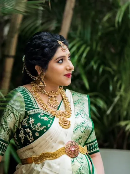 A serene portrait of a mom-to-be during her baby shower photoshoot. The white and green Kanchipuram saree is draped to create a classic and divine look.