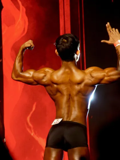 A back shot on stage, displaying the detailed musculature of the lats, traps, and lower back.