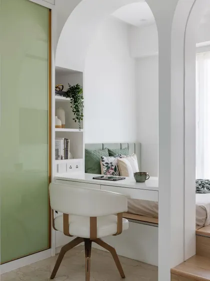 A view of the teen daughter's bedroom, showing the arched divider, the cozy study nook, and the serene green and white color palette.