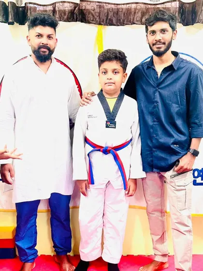 A young student proudly displays his new red and blue belt.