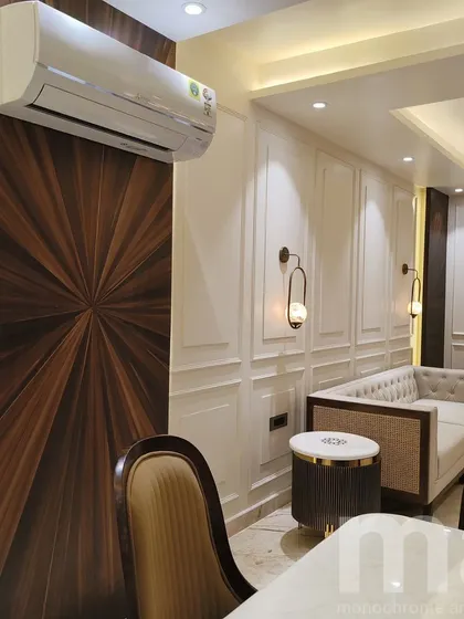 A detail shot showing the combination of a sunburst teak veneer panel and classic wall moulding. This contrast between natural wood grain and painted architectural detail creates a rich, layered effect.
