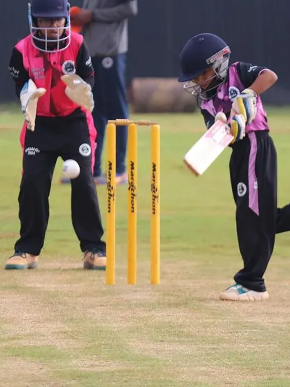 An action shot from a U-10 match, with a young batter playing a shot as the wicketkeeper watches closely. This highlights our focus on grassroots cricket.