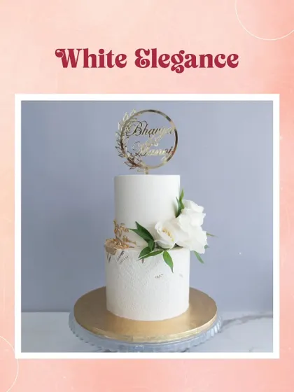 A simple and elegant two-tiered white cake, personalized with a custom topper and adorned with beautiful white roses and greenery.