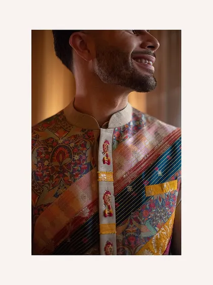 A close-up on the intricate details of the groom's jacket. The small, embroidered figures add a touch of whimsy and character to the classic ensemble.
