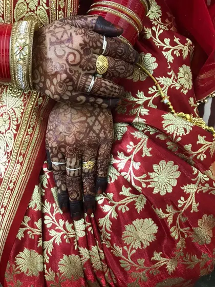 A candid shot showing the beautiful stain on the bride's hands against her red saree.