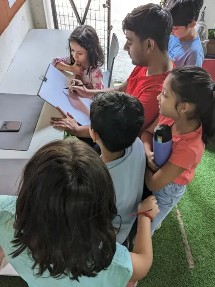 A close-up of the demonstration. The children are eager to see how the drawing comes to life, step by step.