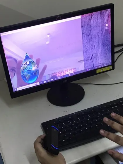 A student uses a hand-held controller to interact with an AI-powered application on the screen, which shows a 3D model of the Earth.