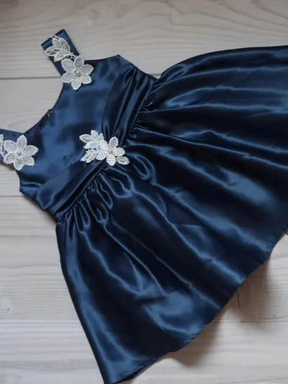 An elegant navy blue satin dress adorned with delicate white lace flowers on the straps and bodice. A simple, sophisticated choice for a formal event.
