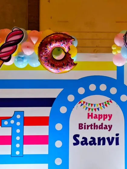 The personalized backdrop for Saanvi's first birthday, featuring her name and fun candy graphics.