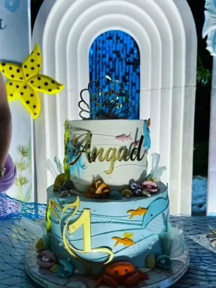 The two-tiered birthday cake, beautifully decorated with an underwater theme, including fish, crabs, and a personalized cake topper.