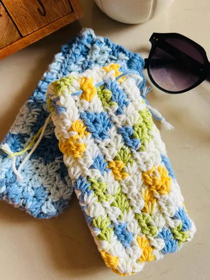A pair of colorful sunglasses pouches, one in shades of blue and another in a multi-color mix of blue, green, and yellow.