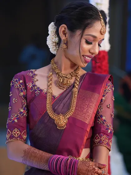 A soft, downward glance, highlighting the beautiful eye makeup and the intricate embroidery on her blouse.