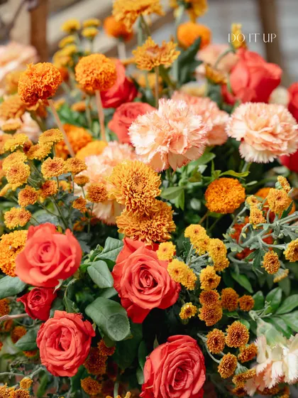 A vibrant bouquet of orange roses and marigolds, capturing the joyful and festive spirit of a Haldi ceremony. The colors are warm, inviting, and full of energy.
