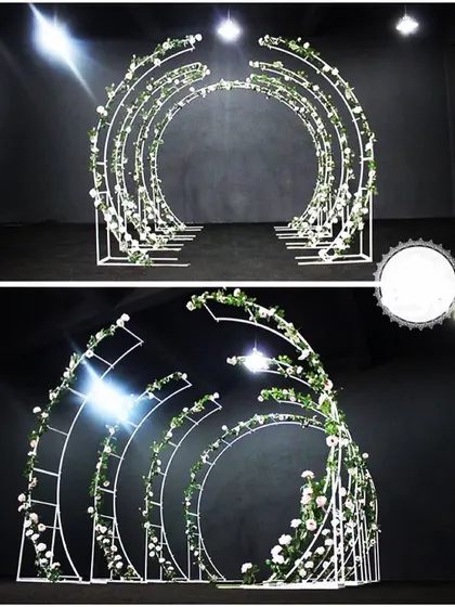 This circular arched walkway, decorated with greenery, offers a modern and elegant frame for an entrance or aisle. It’s a versatile structure that I can customize with different lights and florals.