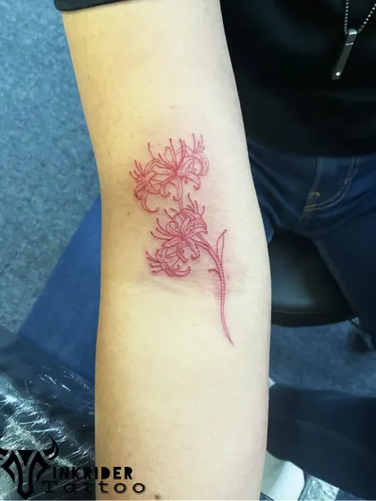 A red spider lily tattoo. This flower carries deep symbolic meaning in many cultures and its vibrant red ink makes for a striking design.