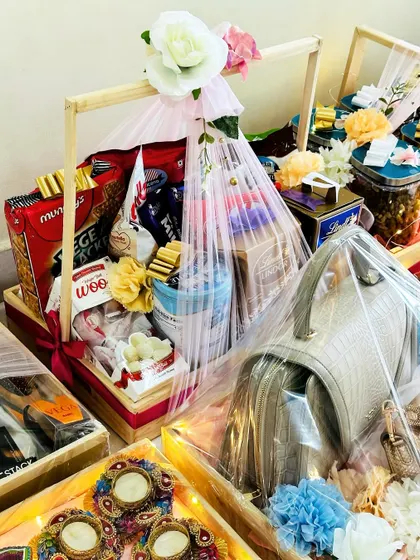 A closer look at a packed trousseau, showing a handbag and other gifts. The clear wrapping is secured with a beautiful floral arrangement.