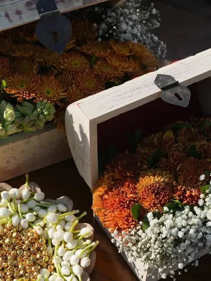 Treasure chests filled with vibrant orange chrysanthemums and delicate tuberoses, used as unique decor pieces along the aisle.