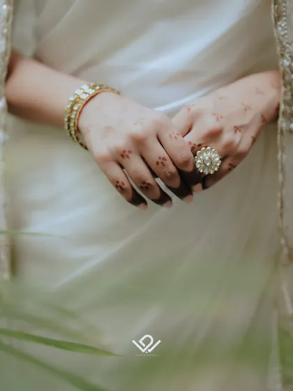 A detail shot focusing on the bride's hands, showing off her henna, bangles, and a stunning statement ring.