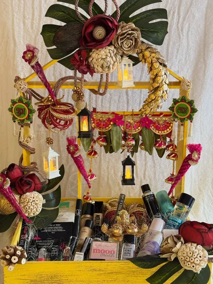 A vibrant and eclectic Diwali hamper for a makeup lover. This yellow-tiered stand is filled with cosmetics and decorated with traditional Indian hangings and miniature lanterns.