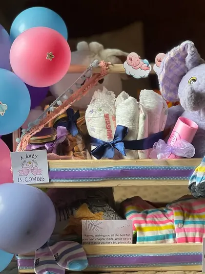 The full view of the two-tiered newborn gift set, complete with colorful balloons. This arrangement makes a wonderful centerpiece for a baby shower or a welcome home gift.