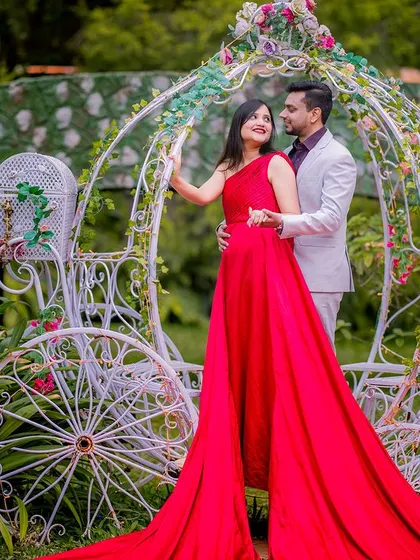 A stunning shot of a couple with a Cinderella carriage, with the bride's red gown adding a pop of color. This is a perfect setup for a fairy-tale themed shoot.