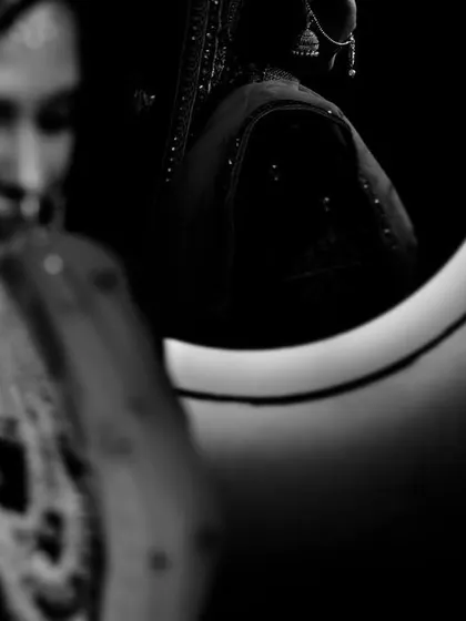 A creative black and white shot of a bride's reflection in a mirror, with her out-of-focus figure in the foreground.