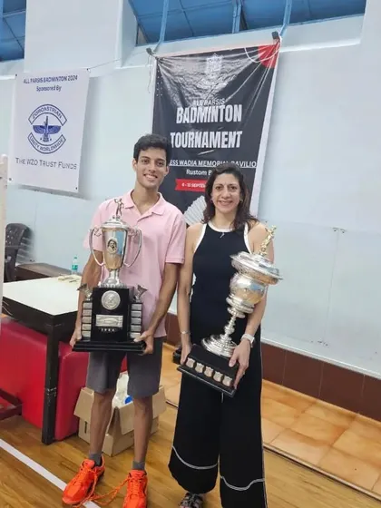 Two generations of champions. Naheed Divecha with a junior player, both holding their respective trophies, showcasing the breadth of talent at our academy.