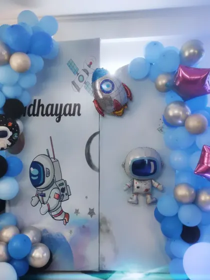 The complete space-themed setup for Adhayan's party. The decor includes a crescent moon, rocket, and astronaut balloons to create an intergalactic adventure.