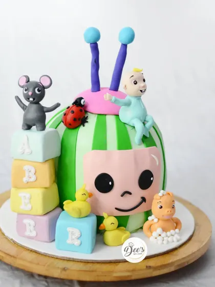 Cocomelon is a favorite for first birthdays. This cake brings the show to life with a sculpted JJ, a watermelon base, and other characters like the mouse and ducks.