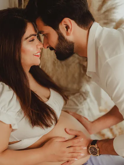 A close-up shot full of love and connection. The focus is on the couple's faces and their hands on the baby bump, telling a story of shared anticipation.