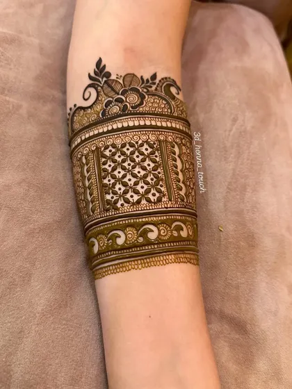 The completed arm band from the video, showcasing a beautiful 'jaal' pattern with a floral border. The fresh henna paste promises a dark and rich stain.