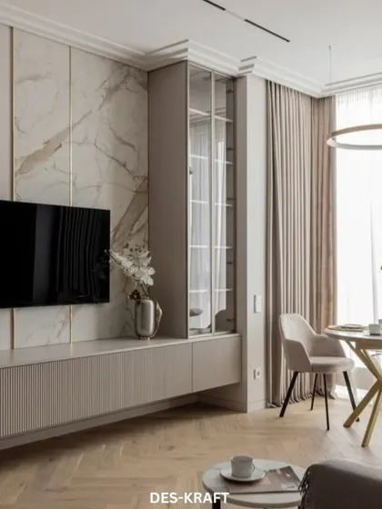 A full view of the living and dining area, showcasing the custom marble-backed TV unit with integrated glass shelving, creating a sophisticated focal point.