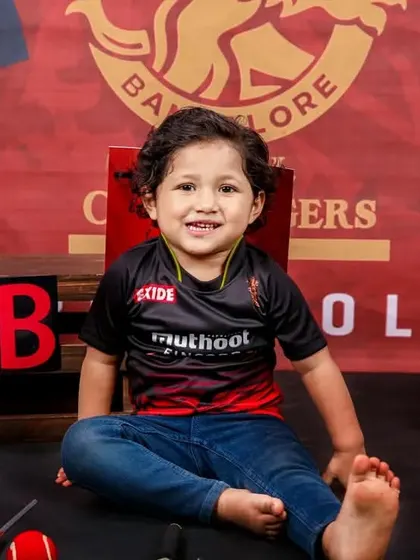A smiling toddler enjoying the RCB cricket-themed photoshoot. His genuine happiness shows how much fun these sessions can be.