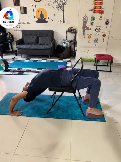 A client performs a supported backbend over a yoga chair, a key practice in Iyengar yoga. This helps to improve spinal flexibility and open the chest in a safe, controlled manner.