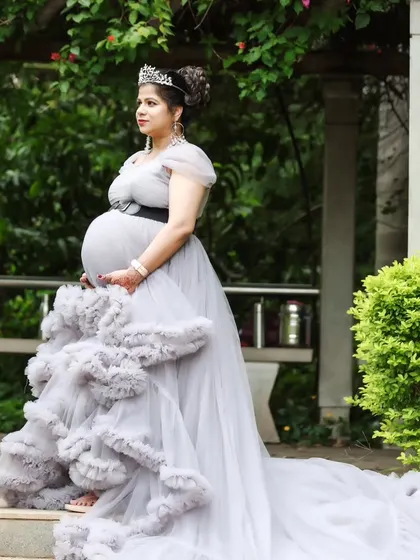 A side profile of the elegant grey ruffled maternity gown, showcasing its intricate details and long train.
